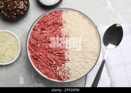 Minced meat with rice in bowl and other ingredients for stuffed cabbage rolls on light grey table, flat lay Stock Photo