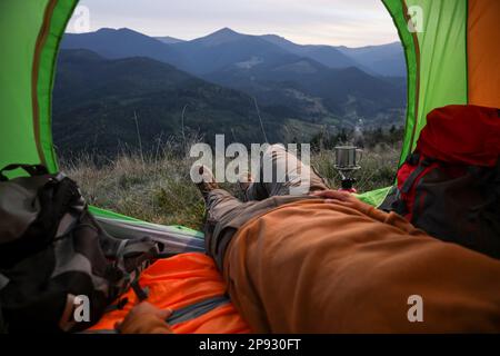 Man resting inside of camping tent in mountains, closeup Stock Photo