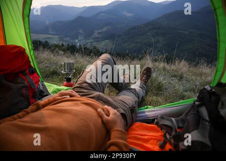 Man resting inside of camping tent in mountains, closeup Stock Photo