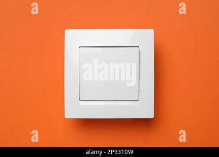 White plastic light switch on orange background Stock Photo