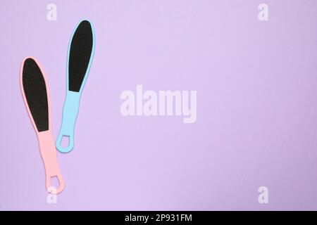 Colorful foot files on violet background, flat lay with space for text. Pedicure tools Stock Photo