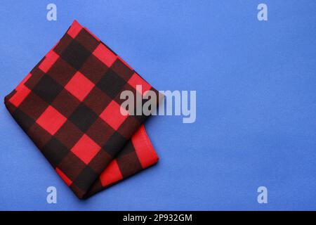 Folded red bandana with check pattern on blue background, top view. Space for text Stock Photo