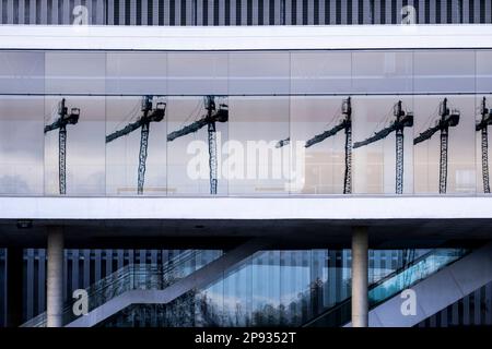 Construction cranes reflected in a modern building Stock Photo