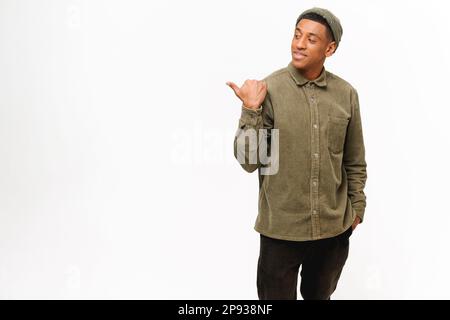 Attractive stylish young hispanic man wearing pointing aside with thumb, showing something, handsome guy paying attention at empty copy space. Advertisement concept Stock Photo