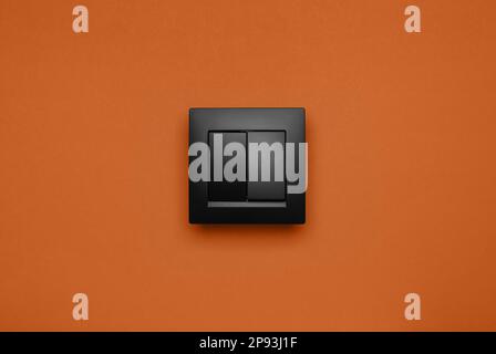 Black plastic light switch on orange background Stock Photo