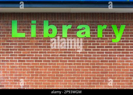 The word Library in large green letters on the brick wall of a public library. Stock Photo