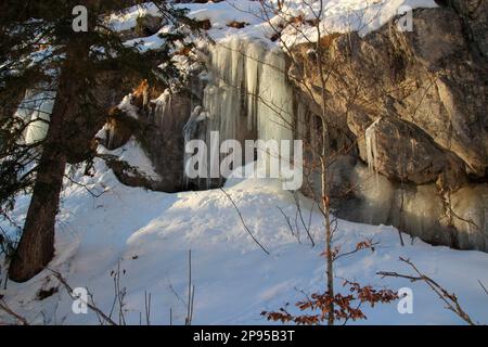 wintry mountain hike near Mittenwald to Hochlandhütte, icicles on rocky outcrop along the way, Europe, Germany, Bavaria, Upper Bavaria, Werdenfels, evening atmosphere Stock Photo