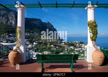 View NNW across Capri  and the Gulf of Naples from the Piazzetta di Capri. A bench in the plaza flanked by columns.  Capri is an island located in the Tyrrhenian Sea off the Sorrento Peninsula, on the south side of the Gulf of Naples in theCampaniaregion of Italy  Capri, is famed for its rugged landscape, cultural history, upscale hotels and shopping Stock Photo