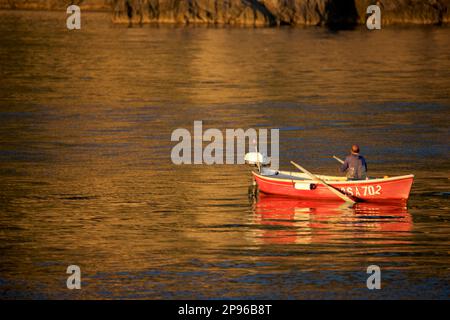 Small boat with man fishing, off Praiano, Amalfi Coast, Salerno, Italy  Late afternoon golden sunlight. Tyrrhenian Sea / Mediterranean Sea. Stock Photo