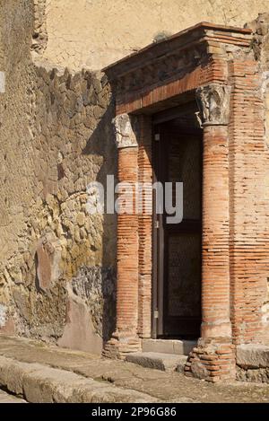 Herculaneum uncovered. Herculaneum was buried under volcanic ash and pumice in the eruption of Mount Vesuvius in AD 79. Ercolano, Campania, Italy . Detail of stone and brick wall.with doorway flanked with brick columns and capitals Stock Photo