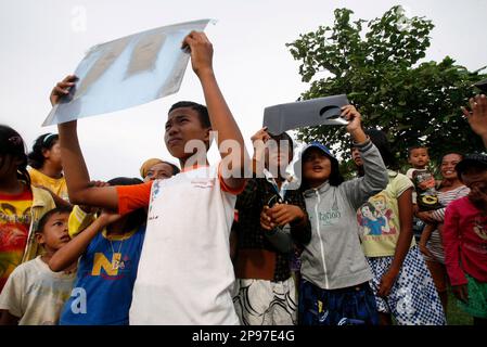 indonesian children look up through x ray film sheets to watch a solar eclipse in the sky in anyer beach banten province indonesia monday jan 26 2009 ap photoachmad ibrahim 2p97e4g