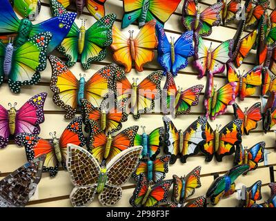 Many colorful painted ceramic butterflies hanging on a wall display and for sale in a Mexican bazaar shop. Stock Photo