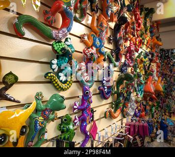 Many colorful painted ceramic reptiles hanging on a wall display and for sale in a Mexican bazaar shop. Stock Photo