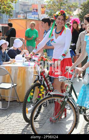 Pretty Ukrainian girl on high heels in red skirt and traditional outfits w/bicycle at City Day celebration in Dnepr (Dnepropetrovsk) in September 2013 Stock Photo