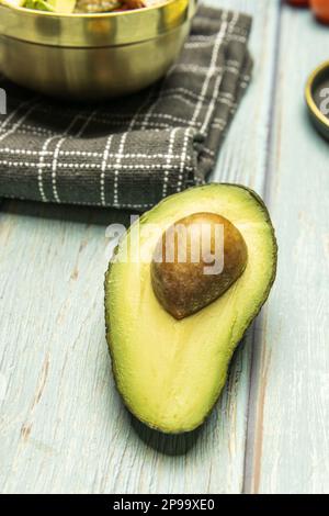 A ripe super avocado cut in half on a light blue table Stock Photo