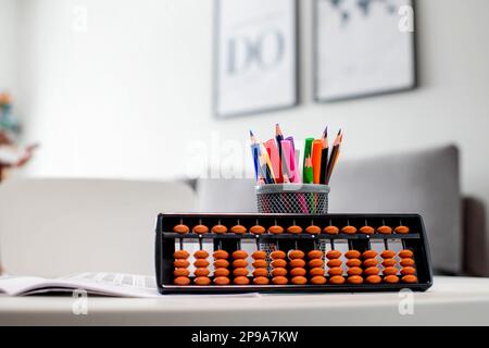 Abacus and colored pencils on a white table. Learning mental arithmetic Stock Photo