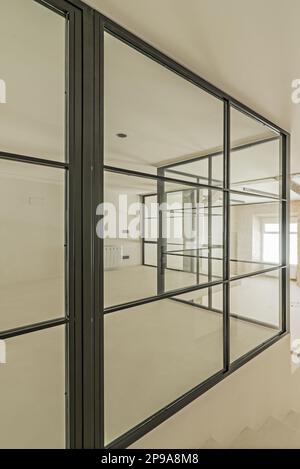 Metal and glass enclosure with a few angles of a loft with polished white cement walls and floors Stock Photo