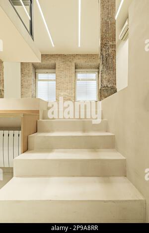 Polished white concrete stairs of a loft with vintage wooden columns and beams Stock Photo