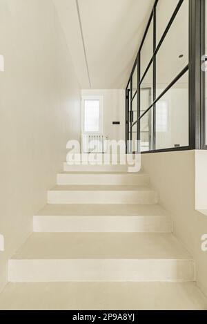 White polished concrete stairs with access to a closed room with metal and glass glazing Stock Photo