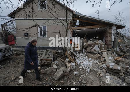 Woman walks through the debris of private houses ruined in Russia's night rocket attack in a village, in Zolochiv district in the Lviv region. Russia continues to attack Ukraine's energy infrastructure. Stock Photo