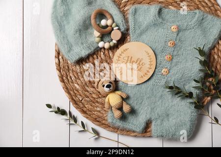 Children's clothes, toys and green plant on white wooden table, top view Stock Photo