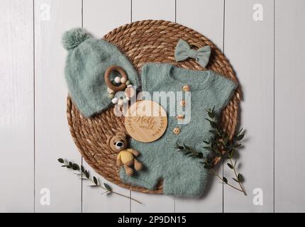 Children's clothes, toys and green plant on white wooden table, top view Stock Photo