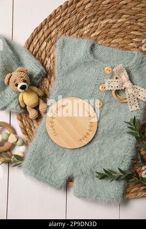 Children's clothes, toys and green plant on white wooden table, top view Stock Photo