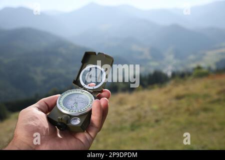 Man using compass during journey in mountains, closeup Stock Photo