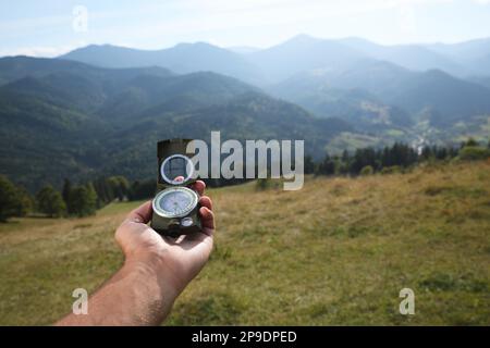Man using compass during journey in mountains, closeup Stock Photo