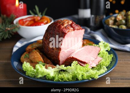 Delicious ham served with lettuce and potatoes on wooden table. Christmas dinner Stock Photo