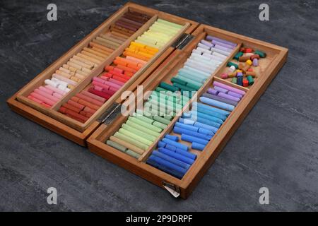 Set of colorful pastels in wooden box on grey stone table. Drawing materials Stock Photo