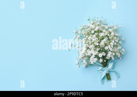 Beautiful gypsophila flowers tied with ribbon on light blue background, top view. Space for text Stock Photo