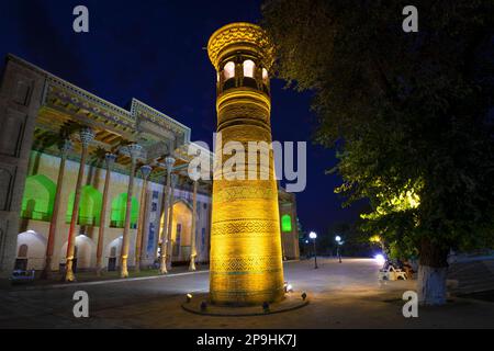 BUKHARA, UZBEKISTAN - SEPTEMBER 10, 2022: Ancient minaret at the Bolo-Khauz mosque in yellow night illumination Stock Photo