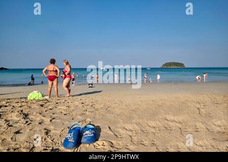 Tourists, mostly Russians, at Kata Yai Beach, Phuket, Thailand, a pair of children's shoes in the sand in the foreground Stock Photo