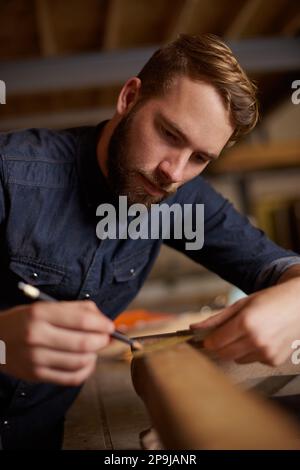Trying his hand at woodwork. a young male carpenter working on a project in his workshop. Stock Photo
