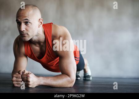 Hes 100 focused on his training. a man doing plank exercises at the gym. Stock Photo
