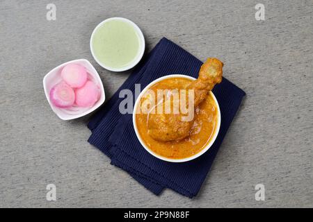 Butter chicken in small bowl served with pickle onion and mint chutney Stock Photo