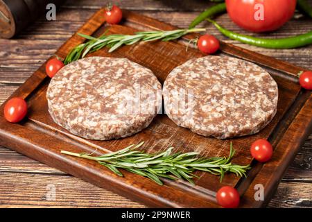 Raw hamburger patties. Beef hamburger patties prepared with spices. Minced Beef burgers on cutting board. Stock Photo