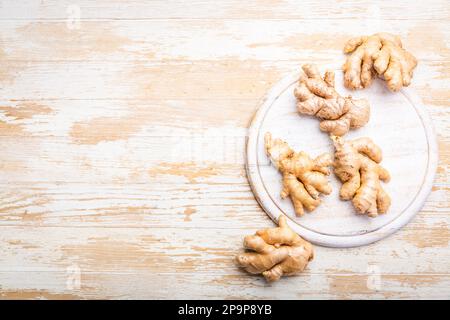 Ginger roots on white wooden background. Stock Photo