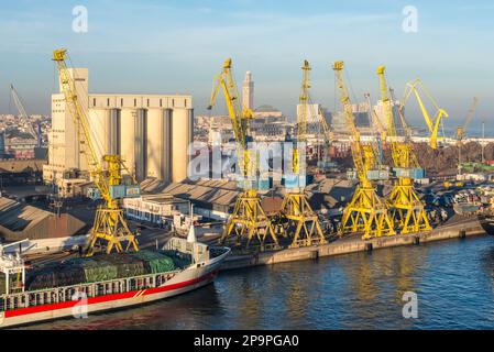 Casablanca, Morocco - December 8, 2016: Embarkation cranes, elevators, and ships in the seaport of Casablanca, Morocco. The Hassan II Mosque in in the Stock Photo