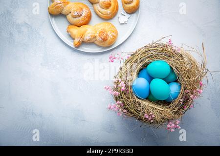 Easter eggs in nest with sweet buns made from yeast dough in a shape of Easter bunny Stock Photo
