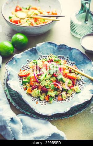 Healthy quinoa black bean salad with fresh tomatoes, cucumbers, onion and cilantro Stock Photo