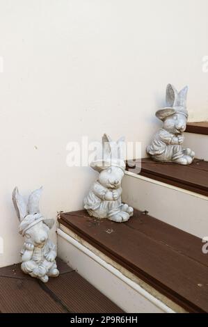 Three of Adorable Easter Bunny Figurines on Wooden Steps Stock Photo