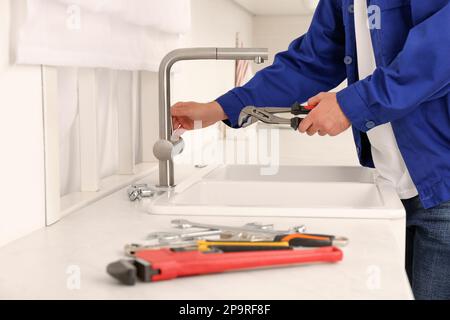 Plumber checking water tap after installation in kitchen, closeup Stock Photo