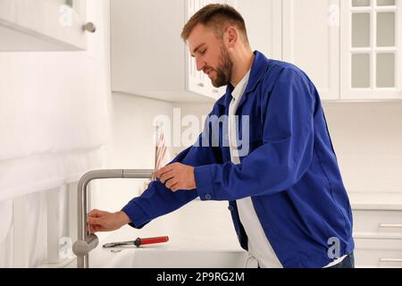 Plumber checking water tap after installation in kitchen Stock Photo