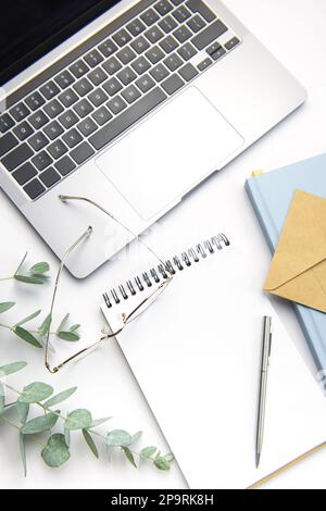 Modern white office desk table with laptop, notebook and other supplies. Blank copy space for  the text. Top view, flat lay. Stock Photo