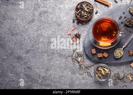 Flat lay composition with freshly brewed tea and dry leaves on grey table. Space for text Stock Photo