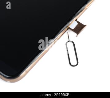 Mobile phone with Sim card in tray and ejector tool on white table, closeup Stock Photo