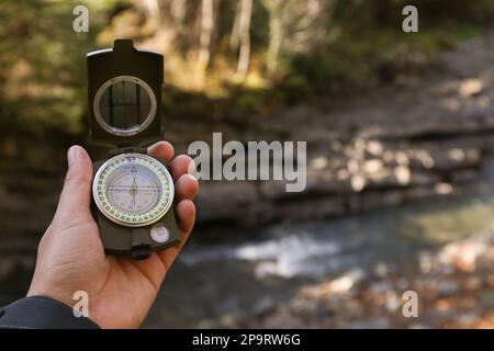 Man using compass for navigation during journey outdoors, closeup Stock Photo