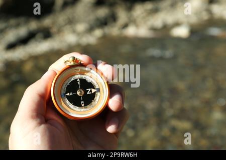 Man using compass for navigation during journey outdoors, closeup Stock Photo